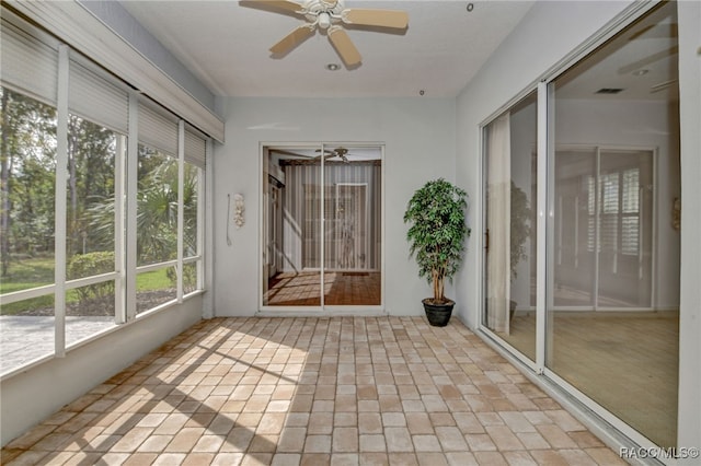 unfurnished sunroom featuring ceiling fan and a healthy amount of sunlight