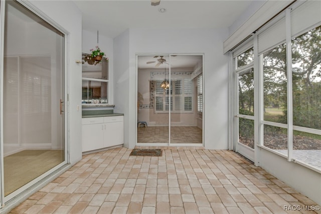 unfurnished sunroom with ceiling fan and a wealth of natural light