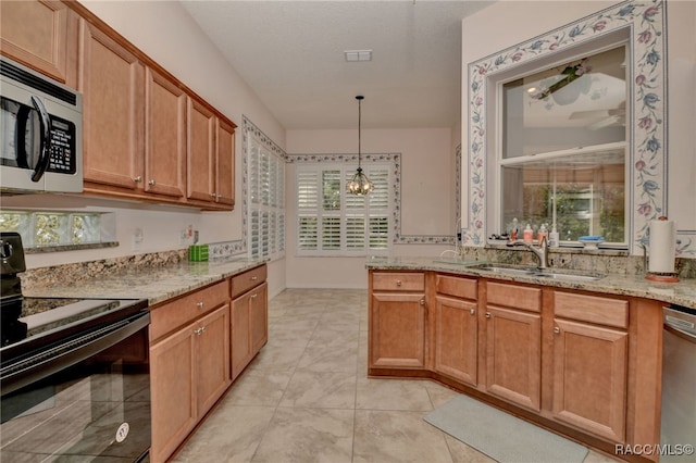 kitchen featuring light stone countertops, appliances with stainless steel finishes, sink, pendant lighting, and a notable chandelier