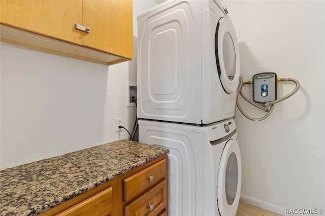 laundry room with cabinets and stacked washer / drying machine