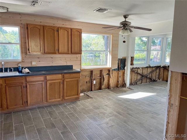 kitchen with wood-type flooring, sink, ceiling fan, and wood walls