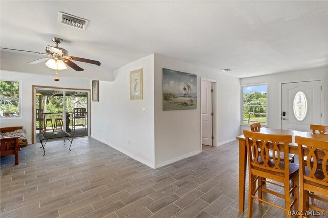 kitchen featuring stainless steel appliances, ceiling fan, wooden walls, sink, and light hardwood / wood-style flooring