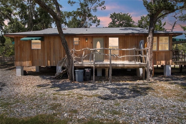 back house at dusk featuring a wooden deck