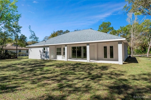 rear view of property with a lawn, french doors, a patio, and stucco siding