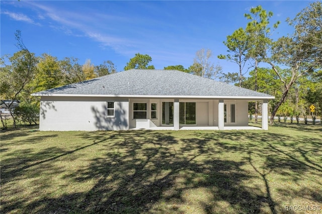 back of house featuring a patio area, roof with shingles, a lawn, and stucco siding