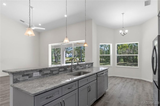 kitchen with stainless steel dishwasher, plenty of natural light, light wood finished floors, and a sink