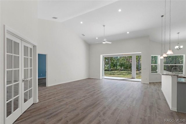 unfurnished living room with baseboards, high vaulted ceiling, and wood finished floors