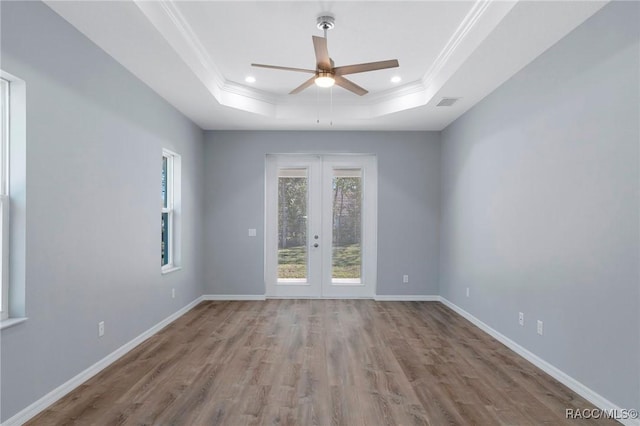 empty room with ornamental molding, wood finished floors, french doors, baseboards, and a raised ceiling