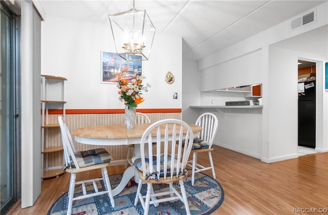 dining space with light hardwood / wood-style floors and a notable chandelier