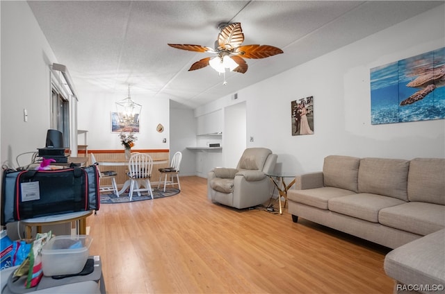 living room with ceiling fan with notable chandelier, hardwood / wood-style floors, and a textured ceiling