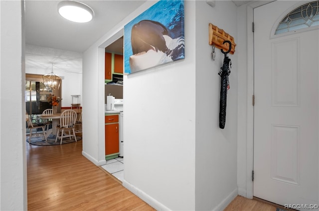 corridor featuring light hardwood / wood-style floors and an inviting chandelier