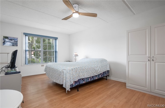 bedroom with ceiling fan, a textured ceiling, and light wood-type flooring