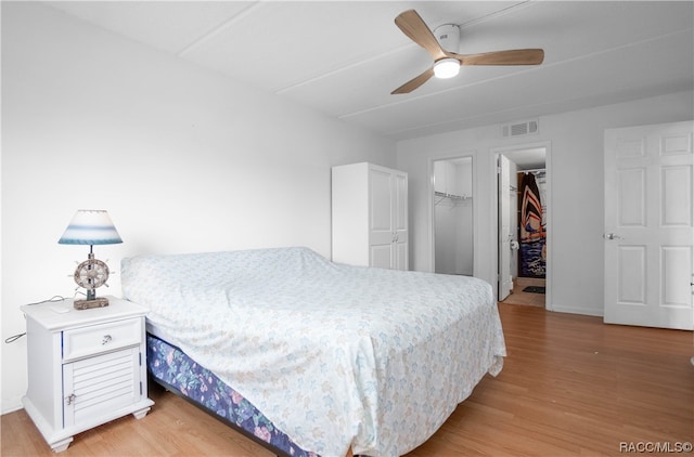 bedroom featuring ceiling fan, light wood-type flooring, a walk in closet, and a closet