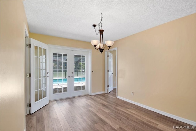 3231 S Eagle Pt, Inverness, FL 34450 - unfurnished dining area featuring french doors, wood finished floors, a textured ceiling, and a chandelier