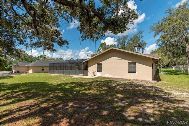 3231 S Eagle Pt, Inverness, FL 34450 - rear view of house featuring stucco siding, a lawn, and glass enclosure