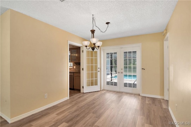 3231 S Eagle Pt, Inverness, FL 34450 - unfurnished dining area with french doors, light wood-type flooring, a textured ceiling, and a chandelier