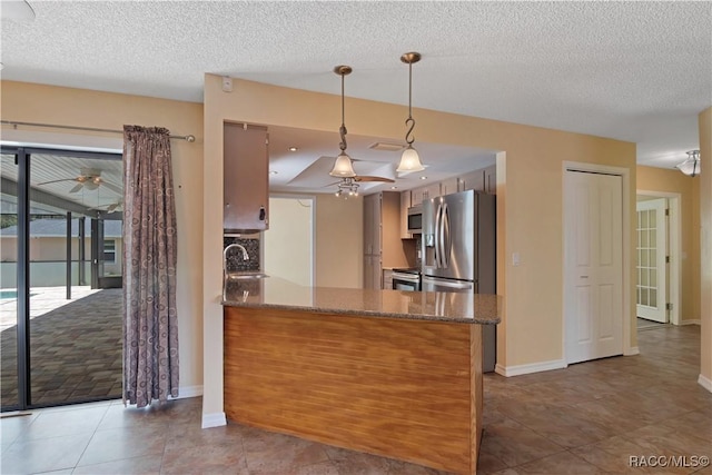 3231 S Eagle Pt, Inverness, FL 34450 - kitchen featuring stainless steel appliances, dark stone counters, a peninsula, decorative light fixtures, and a textured ceiling
