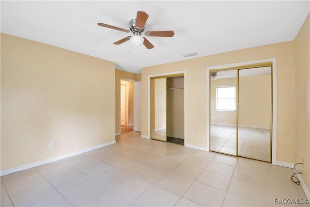 3231 S Eagle Pt, Inverness, FL 34450 - unfurnished bedroom featuring two closets, light tile patterned flooring, and a ceiling fan