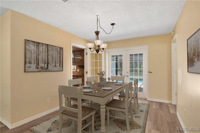 3231 S Eagle Pt, Inverness, FL 34450 - dining area with french doors, light wood-type flooring, a chandelier, and a textured ceiling