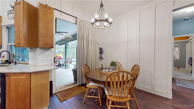 dining area with a textured ceiling, sink, dark wood-type flooring, and an inviting chandelier