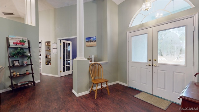 foyer featuring a healthy amount of sunlight, ornate columns, and dark wood-type flooring