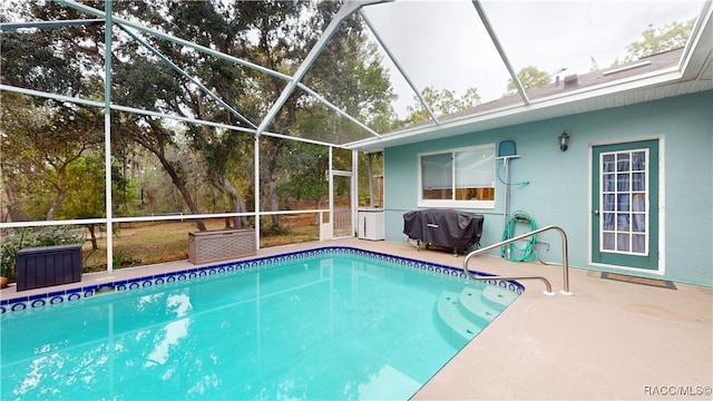 view of swimming pool featuring glass enclosure, a patio area, and grilling area