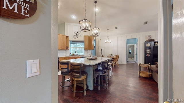 kitchen featuring backsplash, sink, pendant lighting, a center island, and dark hardwood / wood-style floors