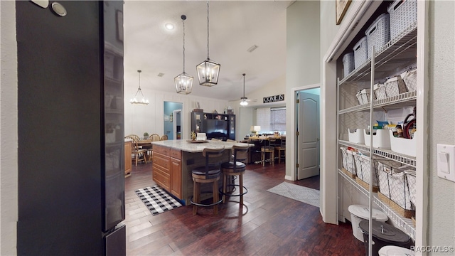 kitchen featuring a kitchen breakfast bar, dark hardwood / wood-style flooring, ceiling fan, high vaulted ceiling, and a center island