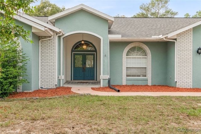 view of exterior entry featuring french doors and a lawn