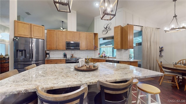 kitchen featuring a breakfast bar, dark wood-type flooring, decorative light fixtures, a kitchen island, and stainless steel appliances