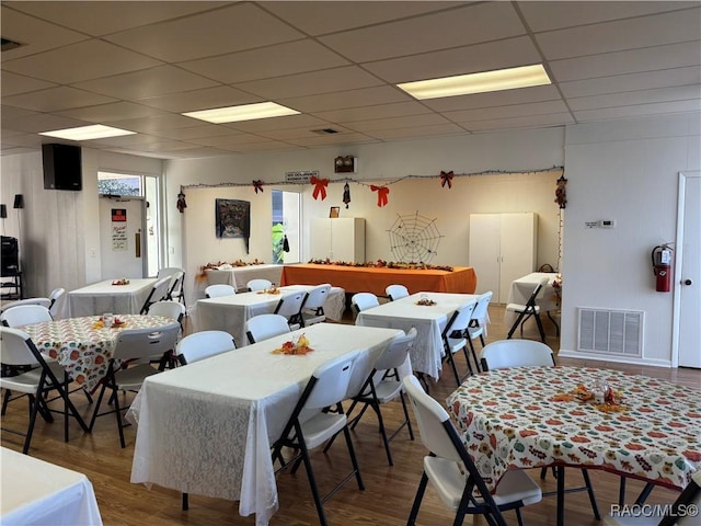 dining room featuring wood-type flooring and a drop ceiling