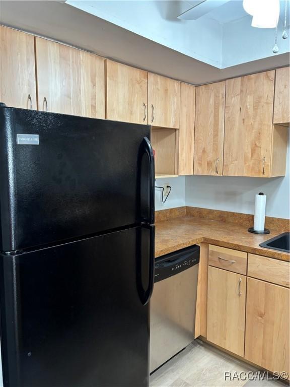 kitchen with black refrigerator, light brown cabinetry, stainless steel dishwasher, and ceiling fan