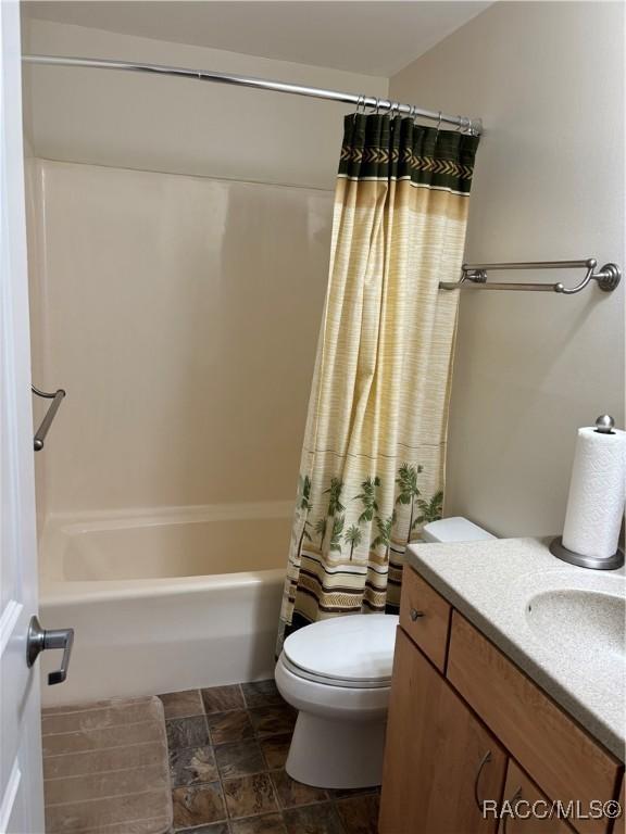 full bathroom with toilet, vanity, and shower / bathtub combination with curtain