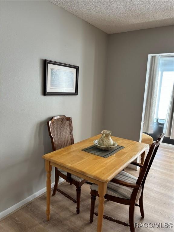 dining space featuring light hardwood / wood-style flooring and a textured ceiling