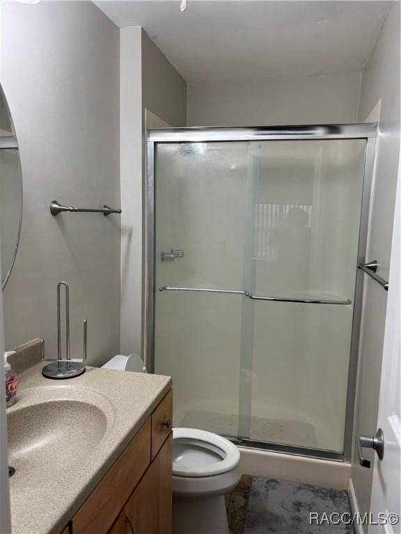 bathroom with vanity, toilet, and a shower with shower door