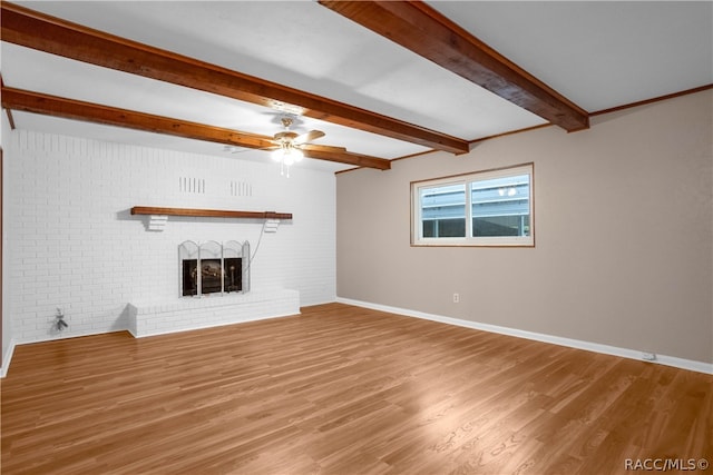 unfurnished living room featuring ceiling fan, beam ceiling, wood-type flooring, and a brick fireplace