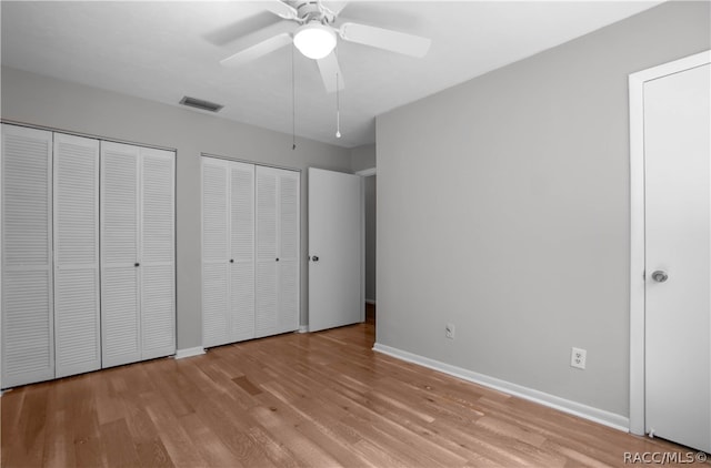 unfurnished bedroom with two closets, light hardwood / wood-style flooring, and ceiling fan