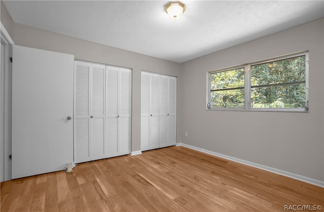 unfurnished bedroom with multiple closets and light hardwood / wood-style floors