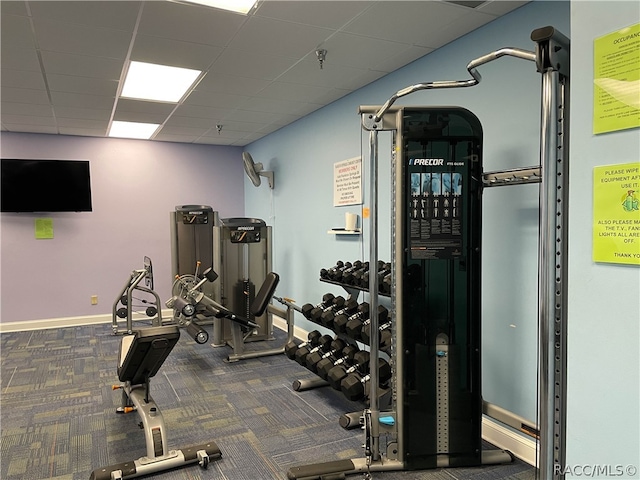 exercise room featuring a paneled ceiling and dark carpet