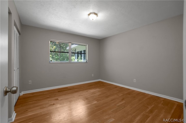 unfurnished bedroom with a textured ceiling, light hardwood / wood-style flooring, and a closet