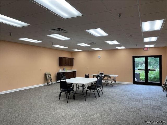 carpeted dining space with a paneled ceiling