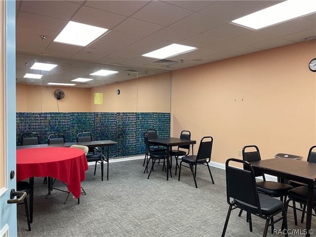 carpeted dining area with a paneled ceiling