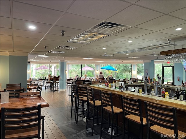 bar with hardwood / wood-style floors, a drop ceiling, and a wealth of natural light