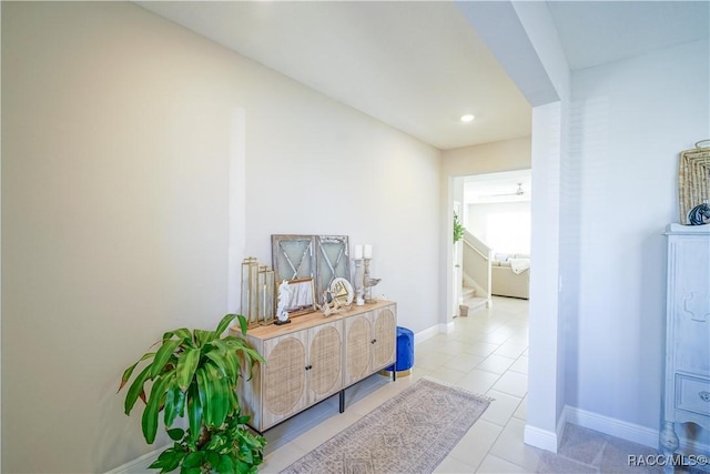 corridor featuring stairway, baseboards, and tile patterned flooring