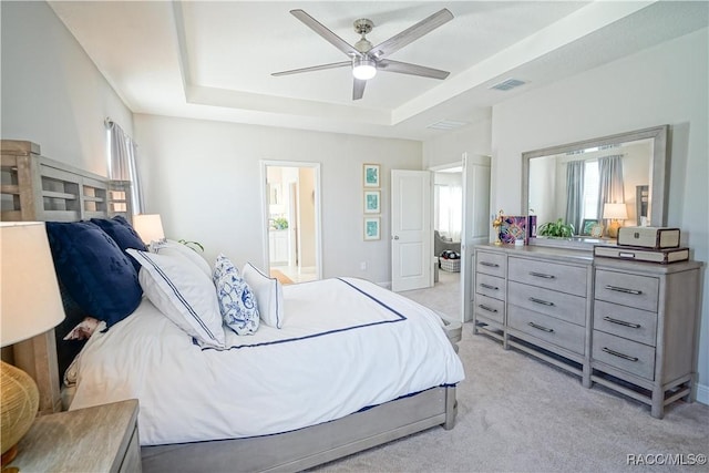 bedroom with visible vents, a ceiling fan, baseboards, a raised ceiling, and light colored carpet