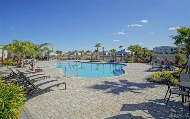 pool with a gazebo, fence, and a patio area