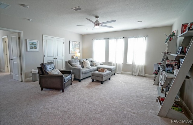 carpeted living area with visible vents, baseboards, a textured ceiling, and a ceiling fan