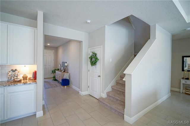 stairs featuring baseboards and a textured ceiling