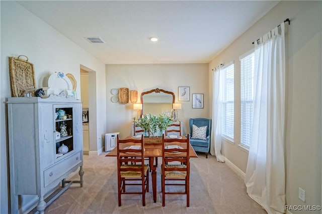 dining room with light carpet, visible vents, and baseboards