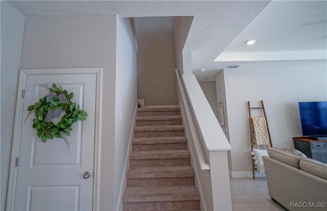 stairs with recessed lighting, baseboards, and a textured ceiling